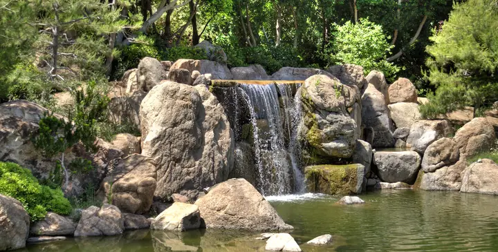 Cascata ampla entre rochas graníticas desaguando em lago